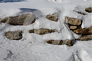 Retaining wall made of granite boulders by the road. the snow fit all around, only the wall remained visible in its beautiful text