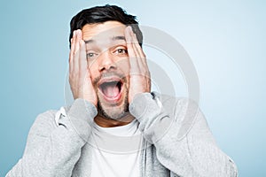 Retarded man making funny faces is silly. a young man looking shocked against a studio background.