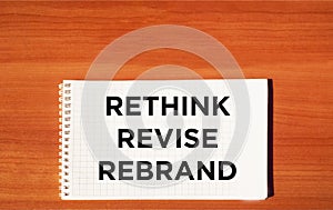 Rethink redefining the rebranding symbol. Rethink Revise Rebrand concept word on notepad and wooden table.Motivational business