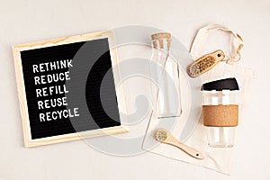 Rethink, reduce, refill, reuse, recycle. Black letter box with eco friendly shopping bag, bottle, coffee cup and brushes