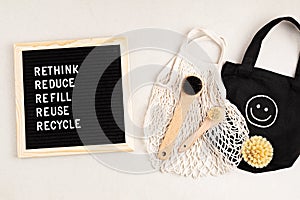 Rethink, reduce, refill, reuse, recycle. Black letter box with eco friendly shopping bag, mesh bag and brushes on white