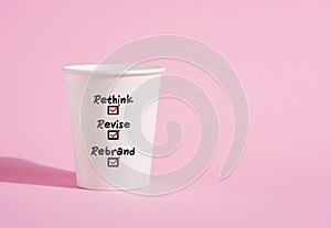 Rethink, revise and rebrand on a paper coffee cup on pink background
