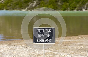 Rethink revise rebrand symbol. Concept word Rethink Revise Rebrand on beautiful blackboard. Beautiful mountain lake background.