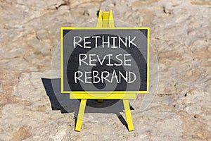 Rethink revise rebrand symbol. Concept word Rethink Revise Rebrand on beautiful blackboard. Beautiful red stone background.