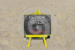 Rethink revise rebrand symbol. Concept word Rethink Revise and Rebrand on beautiful blackboard. Beautiful sand beach background.