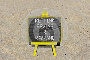 Rethink revise rebrand symbol. Concept word Rethink Revise and Rebrand on beautiful blackboard. Beautiful sand beach background.