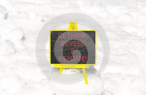 Rethink revise rebrand symbol. Concept word Rethink Revise and Rebrand on beautiful blackboard. Beautiful white snow background.