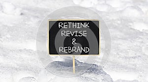 Rethink revise rebrand symbol. Concept word Rethink Revise and Rebrand on beautiful blackboard. Beautiful white snow background.