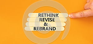 Rethink revise rebrand symbol. Concept word Rethink Revise and Rebrand on beautiful wooden stick. Beautiful orange background.