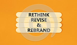 Rethink revise rebrand symbol. Concept word Rethink Revise and Rebrand on beautiful wooden stick. Beautiful orange background.