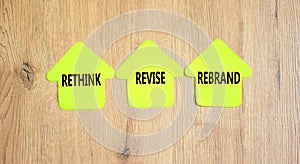 Rethink revise rebrand symbol. Concept word Rethink Revise Rebrand on beautiful yellow paper house. Beautiful wooden background.