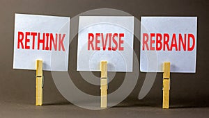 Rethink revise rebrand symbol. Concept word Rethink Revise Rebrand on white paper on clothespin. Beautiful grey background.