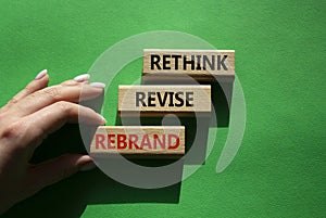 Rethink Revise Rebrand symbol. Wooden blocks with words Rethink Revise Rebrand. Beautiful green background. Businessman hand.