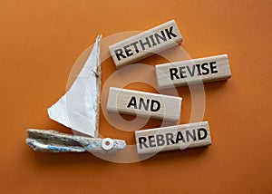 Rethink Revise and Rebrand symbol. Wooden blocks with words Rethink Revise and Rebrand. Beautiful orange background with boat.