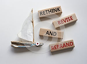 Rethink Revise and Rebrand symbol. Wooden blocks with words Rethink Revise and Rebrand. Beautiful white background with boat.