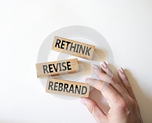 Rethink Revise Rebrand symbol. Wooden blocks with words Rethink Revise Rebrand. Beautiful white background. Businessman hand.