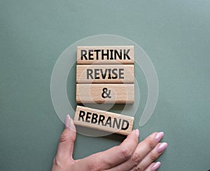 Rethink Revise and Rebrand symbol. Wooden blocks with words Rethink Revise and Rebrand. Businessman hand. Beautiful grey green