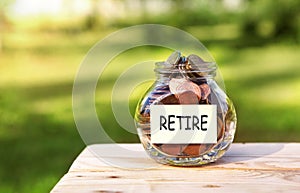 Retire. Glass jar with coins, on a wooden table, on a natural background.