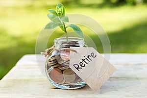 Retire. Glass jar with coins, on a wooden table, on a natural background.