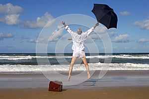 Retired business man jumping with happiness on a tropical beach, retirement freedom concept