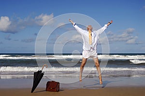 Retired businessman jumping with happiness on a beautiful tropical beach, retirement freedom concept