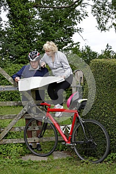 Retired couple on a cycle ride reading their map