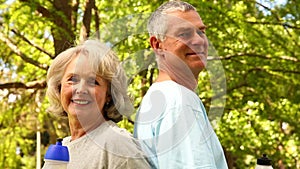 Retired couple drinking water outside