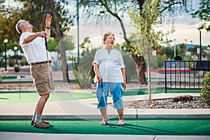 Retired couple having fun playing mini golf photo