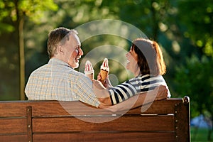 Retired couple on the park bench eating ice-cream.