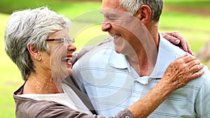 Retired couple in the park smiling at each other