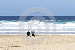 Retired couple sitting on the beach watching the ocean and waves