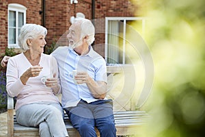 Retired Couple Sitting On Bench With Hot Drink In Assisted Living Facility photo