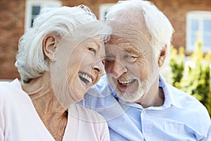 Retired Couple Sitting On Bench And Talking In Assisted Living Facility