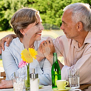 Retired couple sitting at table holding hands