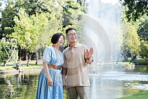 A retired couple walks outside together in the park on a relaxing vacation.