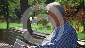 Retired elderly man relaxing outdoors reading a book enjoying retirement