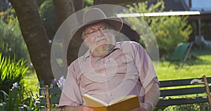 Retired elderly man relaxing outdoors reading a book enjoying retirement