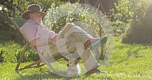 Retired elderly man relaxing outdoors reading a book enjoying retirement