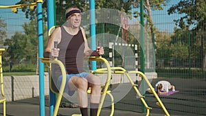 A retired elderly man works out on a sports ground outside. Healthy lifestyle concept.