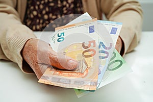 Retired elderly woman holding Euro banknotes money and worry about monthly expenses and treatment fee payment