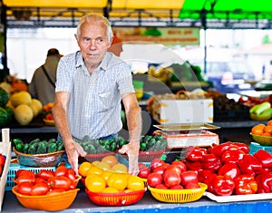 Retired european man selling tomatoes in market