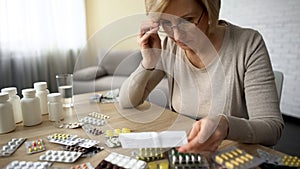 Retired female in glasses reading medicine instruction, pharmaceutical industry