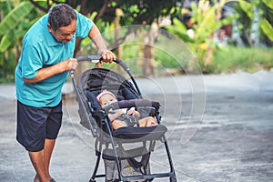 Retired grandfater with little cute niece on stroller outdoor