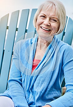 Retired and having the time of my life. Portrait of a happy senior woman relaxing on a chair outside.