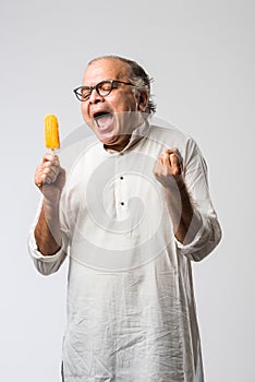 Retired Indian old man eating ice cream, standing icolated against white background