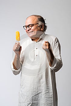 Retired Indian old man eating ice cream, standing icolated against white background