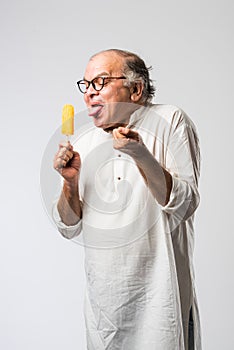 Retired Indian old man eating ice cream, standing icolated against white background