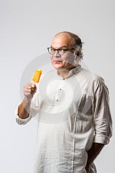 Retired Indian old man eating ice cream, standing icolated against white background