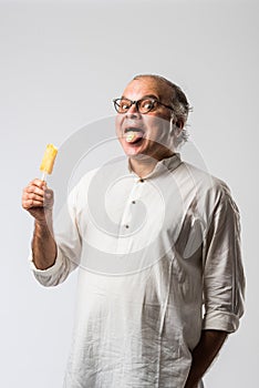 Retired Indian old man eating ice cream, standing icolated against white background