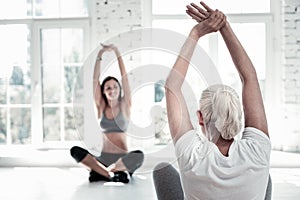 Retired lady training and stretching at fitness club